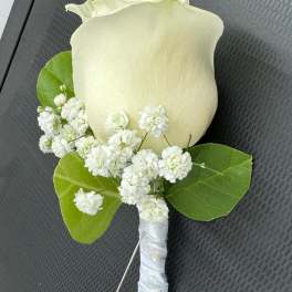 White rose boutonniere with baby's breath and green leaves