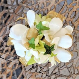 White floral corsage with gold ribbon and ivy accents