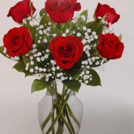 Red roses arranged in a clear glass vase with white baby's breath