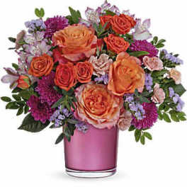 Orange and pink mixed flower bouquet in a pink glass vase