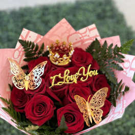 Bouquet of red roses with gold butterfly decorations and a "I Love You" topper
