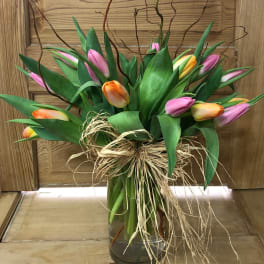 Bouquet of multicolored tulips in a glass vase with raffia bow