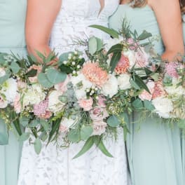 Bridesmaids holding pastel bouquets with roses and greenery