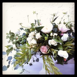 White and pink roses arranged with greenery in a low vase.