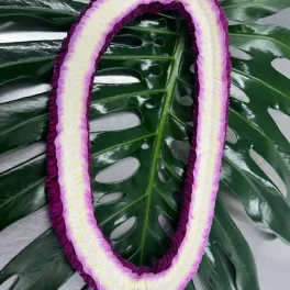 Purple-and-white floral lei on large tropical leaves