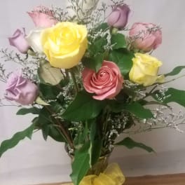 Bouquet of pastel roses in a glass vase with a yellow ribbon