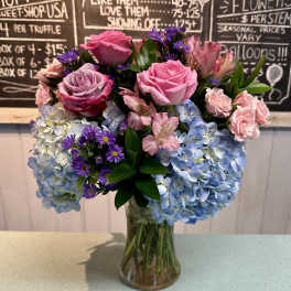 Pink roses and blue hydrangeas arranged in a glass vase