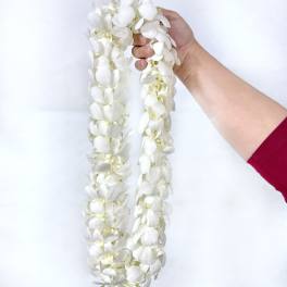 Hand holding two white flower garlands against a plain background