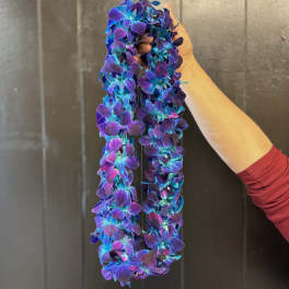 Two purple and blue flower garlands are held up by a hand.
