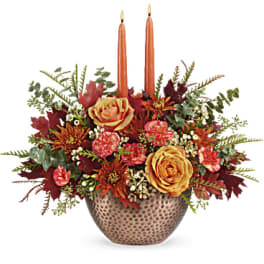 Autumn floral centerpiece in a textured bowl with two orange taper candles