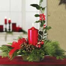 Holiday centerpiece with a red candle, pinecones, and evergreen branches