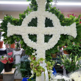 Large white floral cross with green leaves and orchids