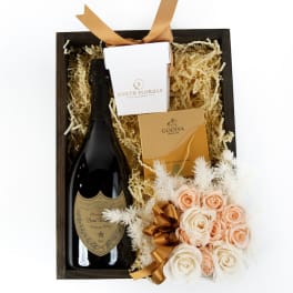 Gift box with champagne bottle, chocolates, and small peach and white rose bouquet