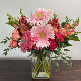 Pink gerbera daisies and mixed pink flowers in a clear glass vase