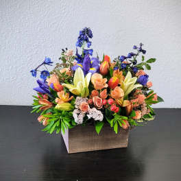 Mixed bouquet in a wooden box with peach, purple, and white flowers