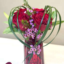 Red roses and pink filler flowers in a red glass vase