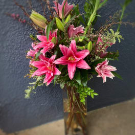 Pink lilies arranged in a tall glass vase