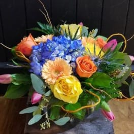 Colorful bouquet with blue hydrangea, roses, and tulips in a glass vase