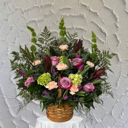Basket arrangement of pink roses, tulips, carnations, and green hydrangeas
