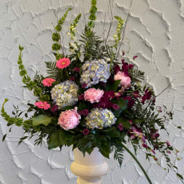 Mixed floral arrangement in a white pedestal vase with pink and purple blooms