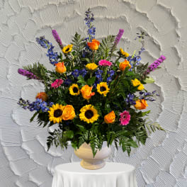 Colorful mixed flower arrangement in a cream vase