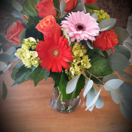 Bouquet of red roses and pink gerbera daisies in a glass vase
