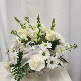 White floral arrangement in a basket with daisies and roses