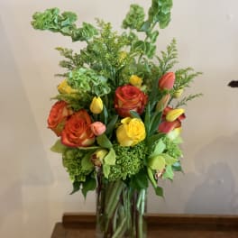 Mixed bouquet of orange and yellow roses in a clear glass vase