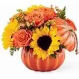 Pumpkin-shaped vase with sunflowers and orange roses