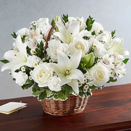 White lilies and roses arranged in a wicker basket