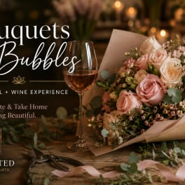 Pink and cream rose bouquet beside a wine glass and candle
