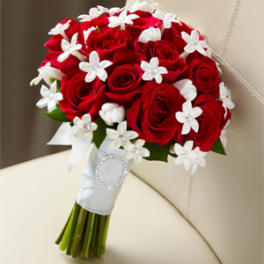 Red roses with white star-shaped accents in a wrapped bouquet