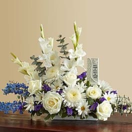 White floral arrangement with blue and purple accents in a rectangular container
