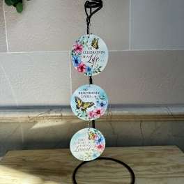 Three round memorial plaques with butterflies and flowers hang from a black stand.
