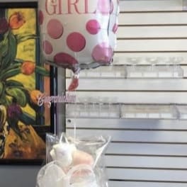 Baby bottle-shaped balloon above a diaper cake wrapped in clear plastic