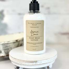 Bottle of goat milk lotion on a small white pedestal