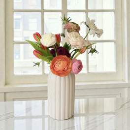 Mixed bouquet of orange, pink, and white flowers in a white vase