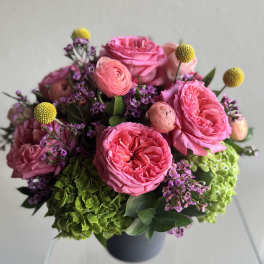 Pink roses and purple filler flowers arranged in a dark vase