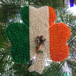 Floral tribute in green, white, and orange with a ribbon bow