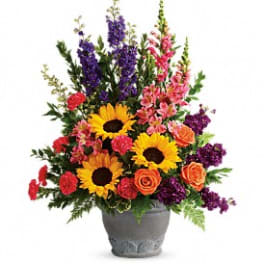 Colorful flower arrangement in a gray vase with sunflowers, roses, and tall purple blooms