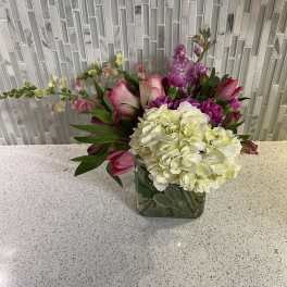 Pink and white floral arrangement in a square glass vase