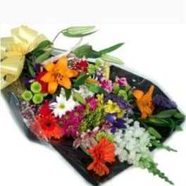Mixed bouquet of colorful flowers wrapped in black paper with a yellow bow