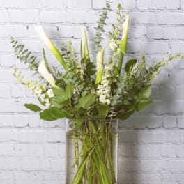 Tall white calla lily arrangement in a clear glass vase