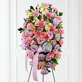 Tall standing spray of pink and lavender flowers with a ribbon