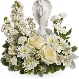 White floral arrangement with an angel figurine in the center
