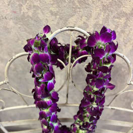 Purple orchid lei draped over a white metal chair