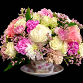 Pink and cream rose bouquet in a teacup on a saucer