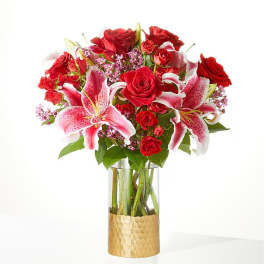 Bouquet of red roses and pink lilies in a clear glass vase