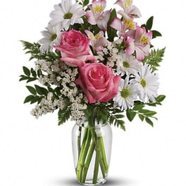 Pink roses and white daisies arranged in a clear glass vase