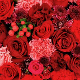 Dense red bouquet with roses, carnations, and small berry accents
